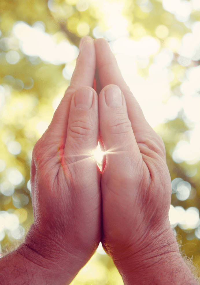 Hands pressed together in gratitude with sunlight between them