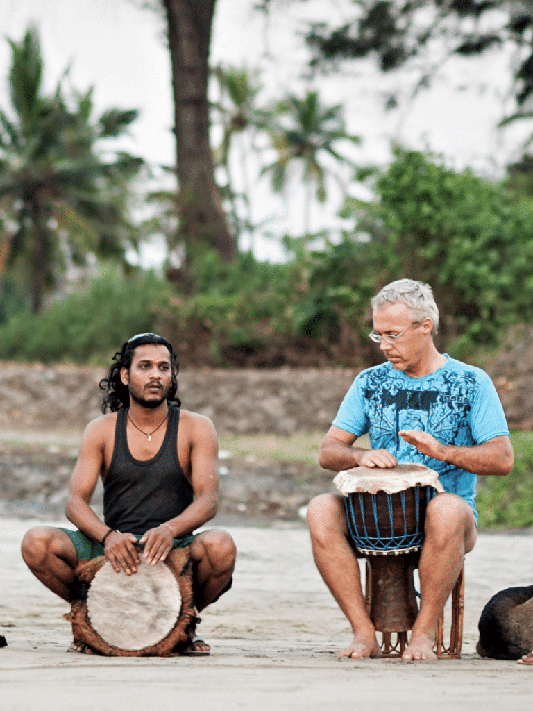 Two men playing hand drums together outdoors in a music healing session