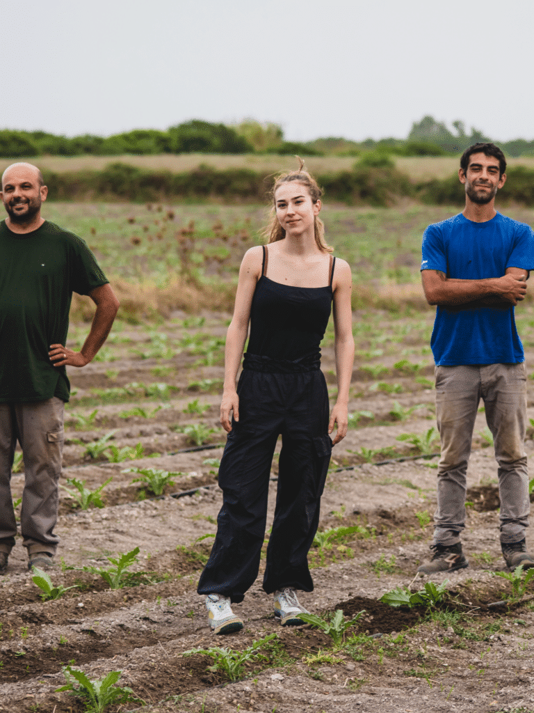 Three people standing in a planted field practicing regenerative living