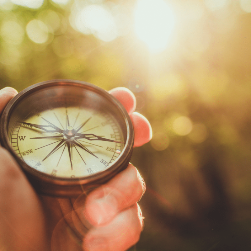 Hand holding a compass in warm sunlight