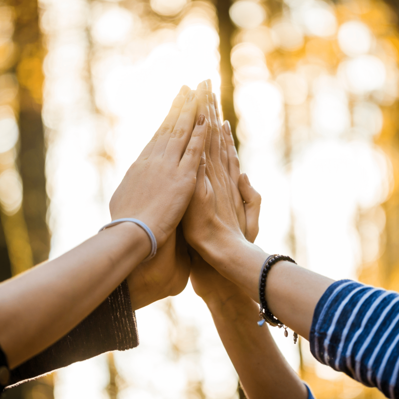 Two people pressing their hands together in a high five outdoors