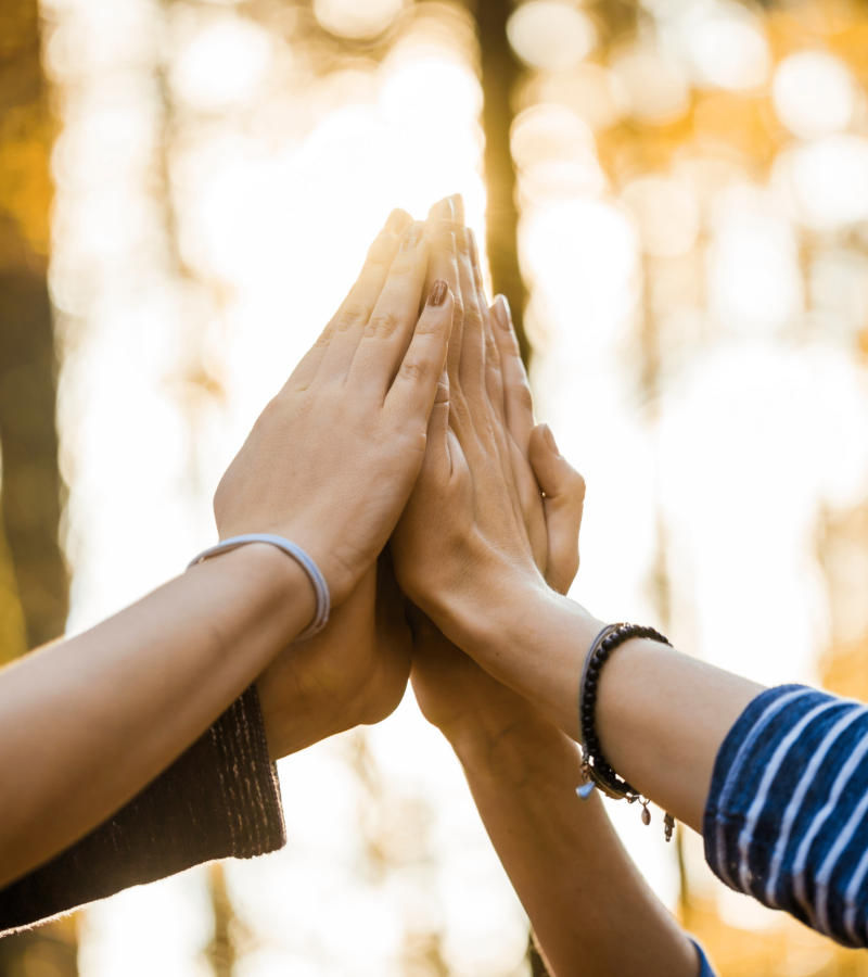 Two people pressing their hands together in a high five outdoors